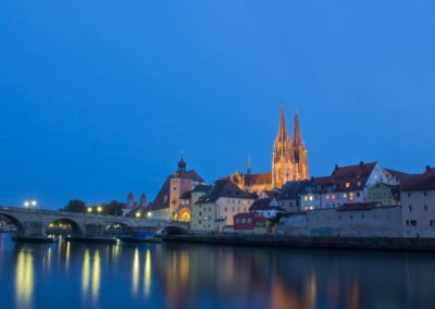 Stone bridge of Regensburg and cathedral by night